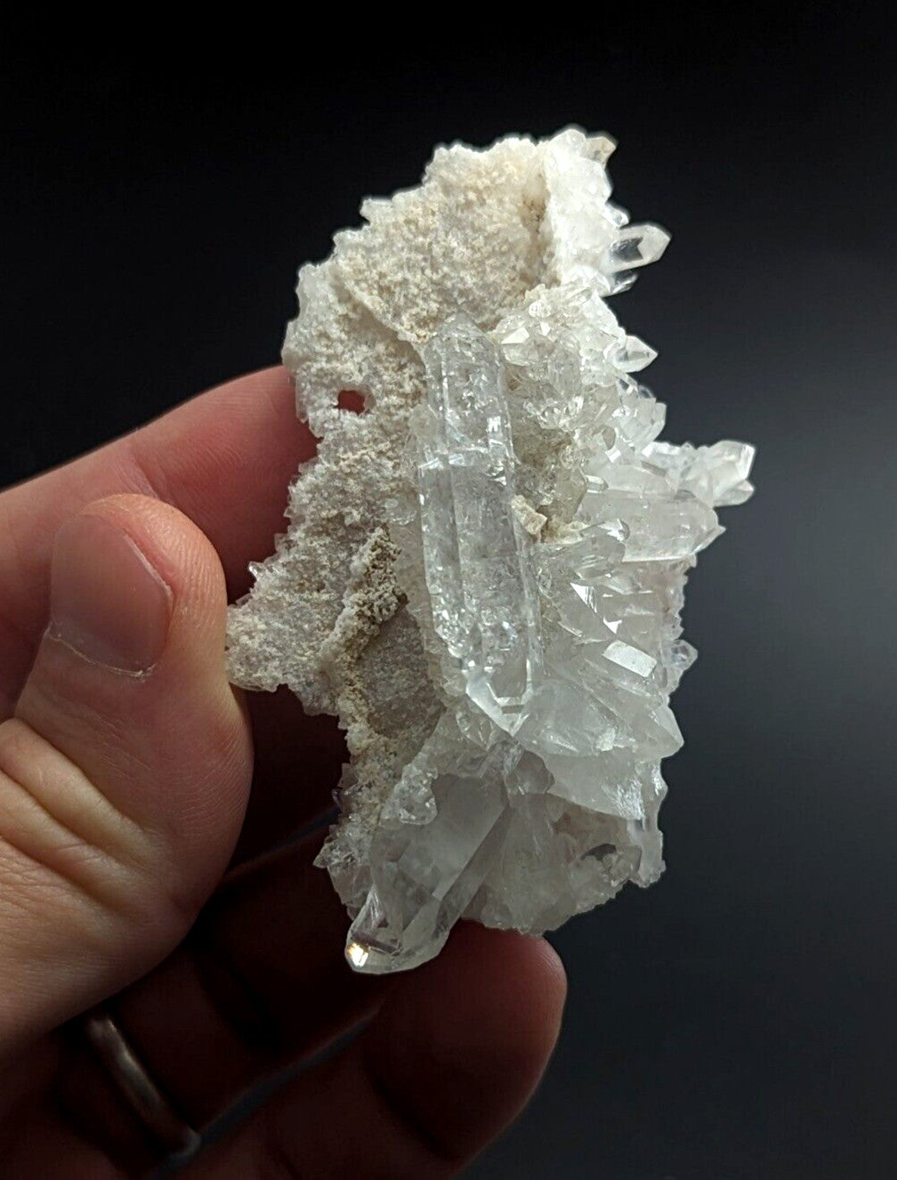 A translucent white quartz crystal cluster with sharp, faceted points emerging from a rougher, porous matrix.