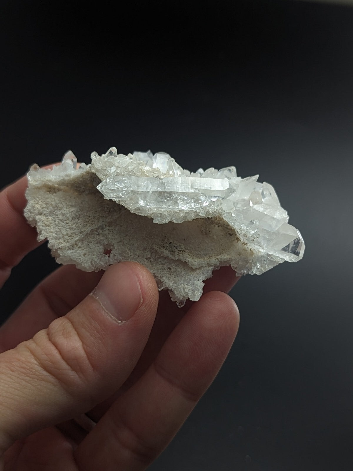 A translucent white quartz crystal cluster with sharp, faceted points and a rough, porous base.