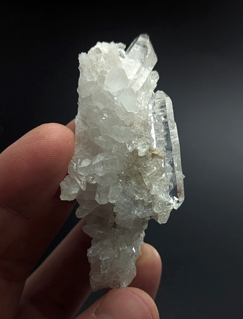 A translucent white quartz crystal cluster with sharp, faceted points and a rough-textured base.