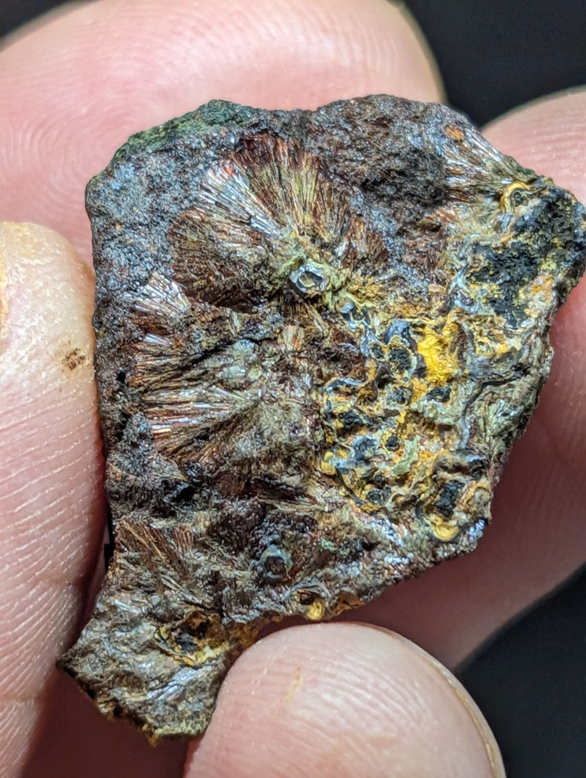 A rugged, irregularly shaped mineral specimen with a textured surface displaying patches of greenish-blue patina and vibrant yellow-orange streaks.