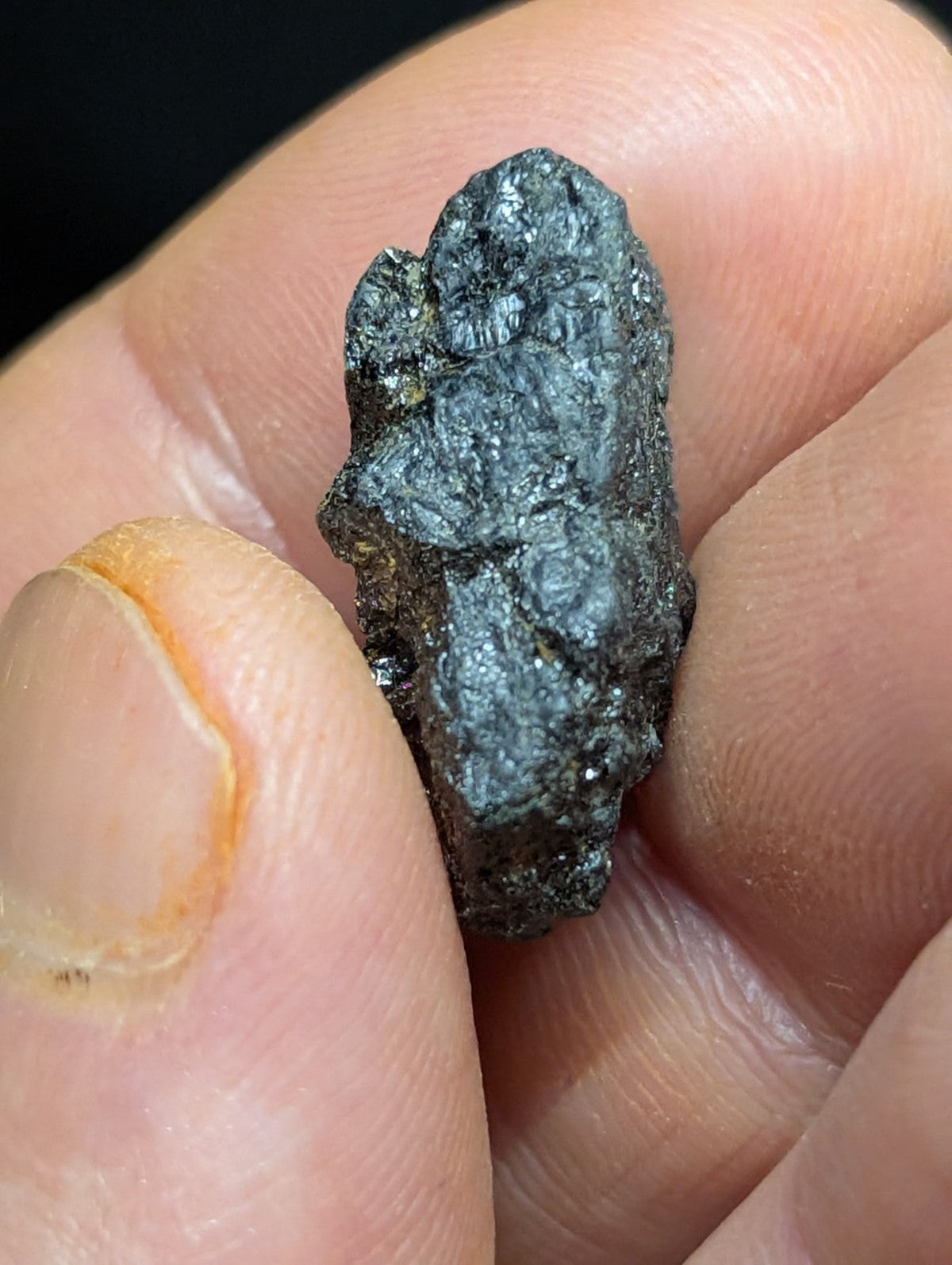 A dark, irregularly shaped meteorite with a rough, textured surface and metallic sheen.