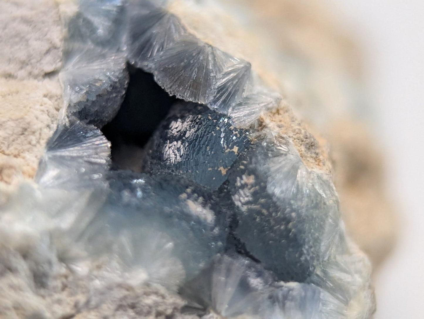 A translucent blue-gray mineral specimen with crystalline formations emerging from a rocky matrix.