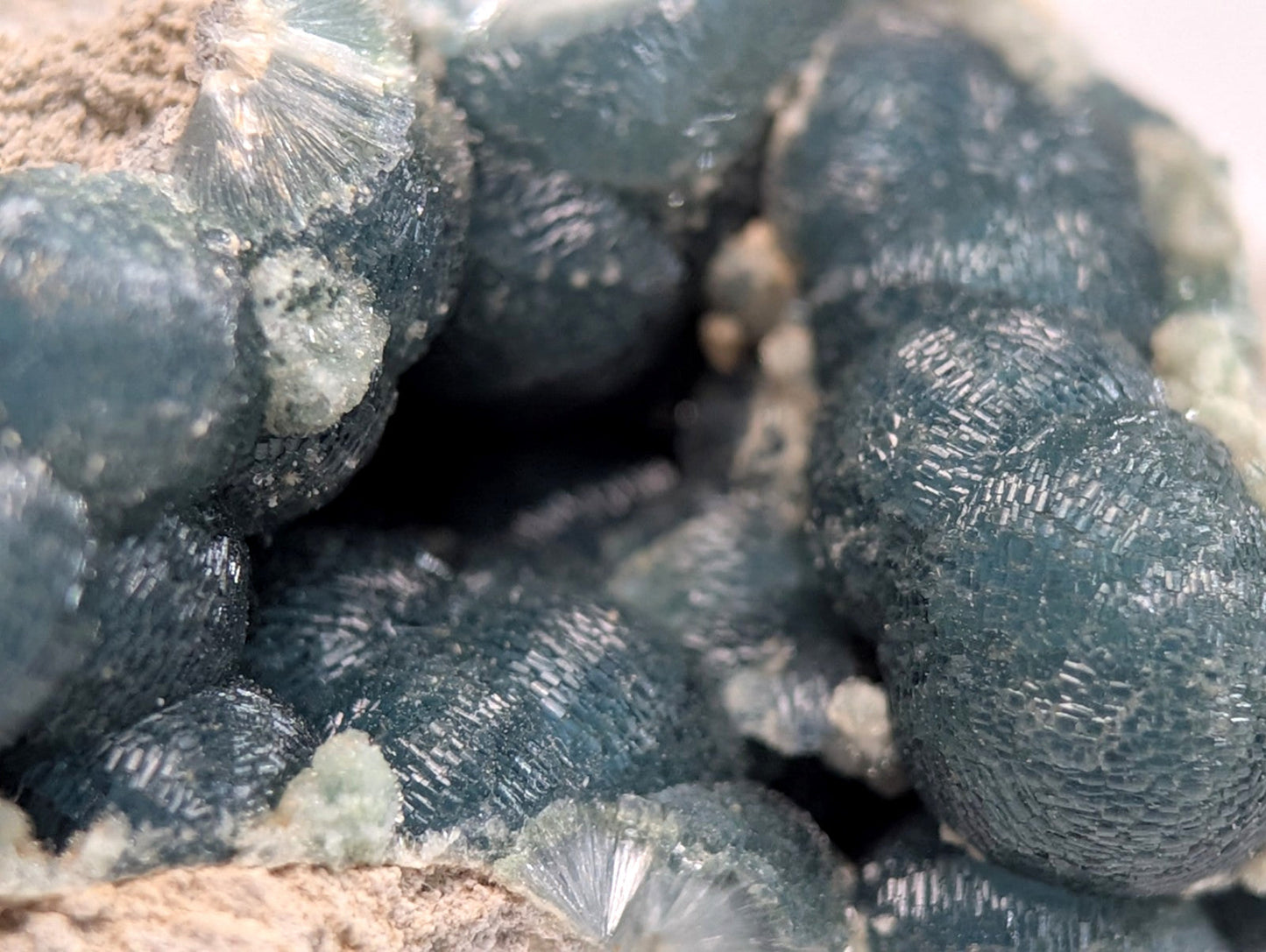 Dark blue, translucent mineral crystals with intricate radial patterns and a rough, earthy matrix.