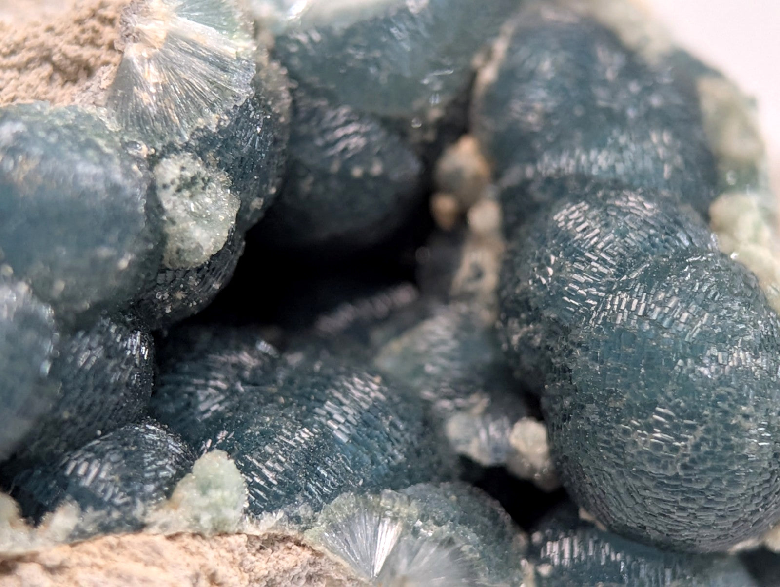 Dark blue, translucent mineral crystals with intricate radial patterns and a rough, earthy matrix.