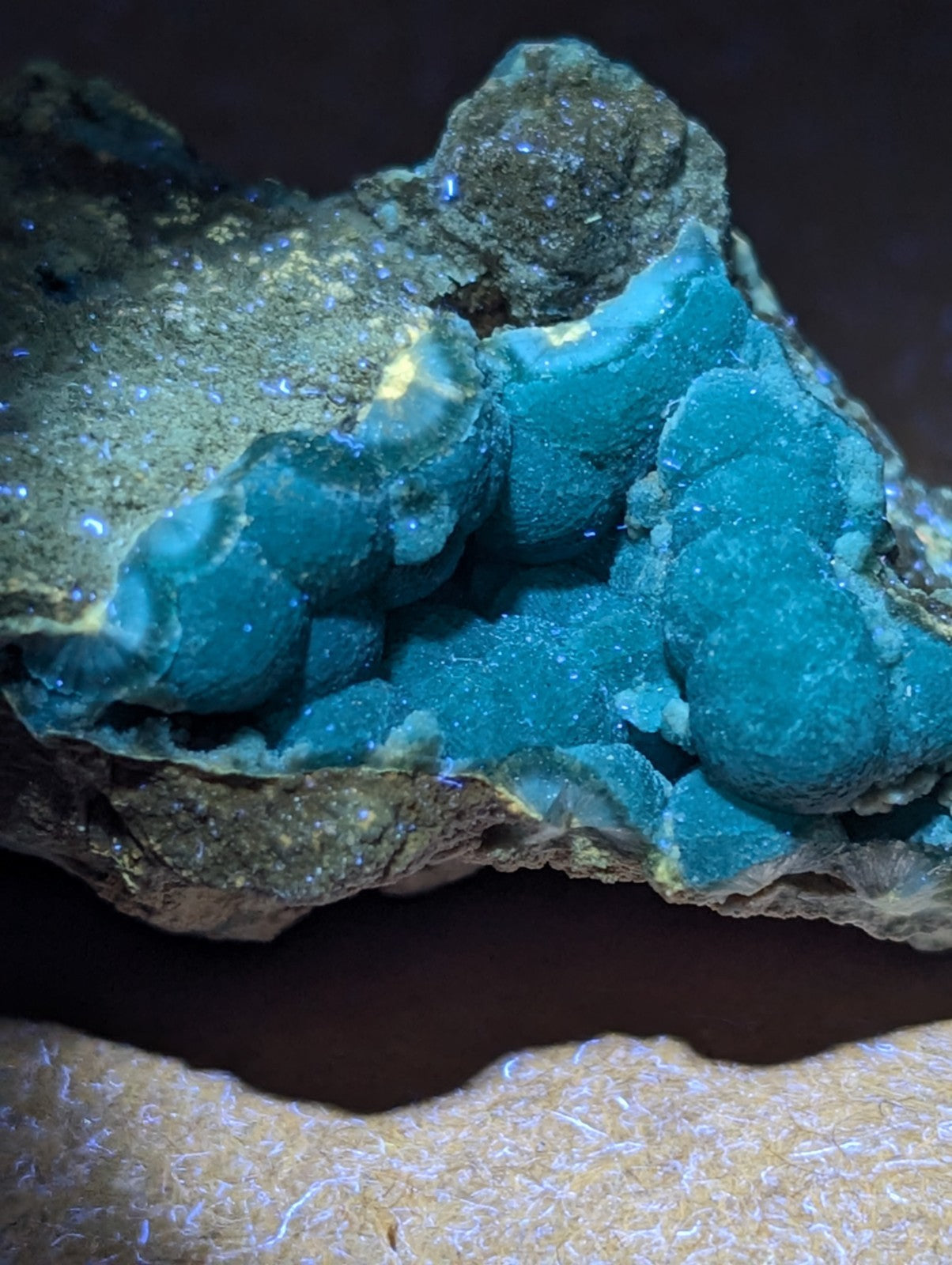 Vibrant turquoise mineral formation with a rough, earthy matrix and sparkling blue crystalline clusters.