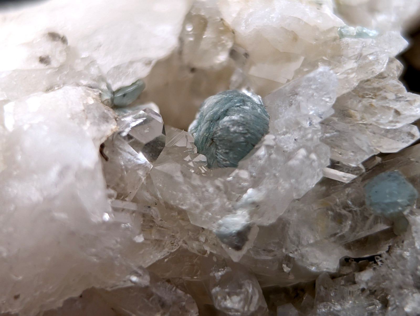 A cluster of translucent pale blue-green cookeite crystals nestled among clear quartz formations from saline county arkansas