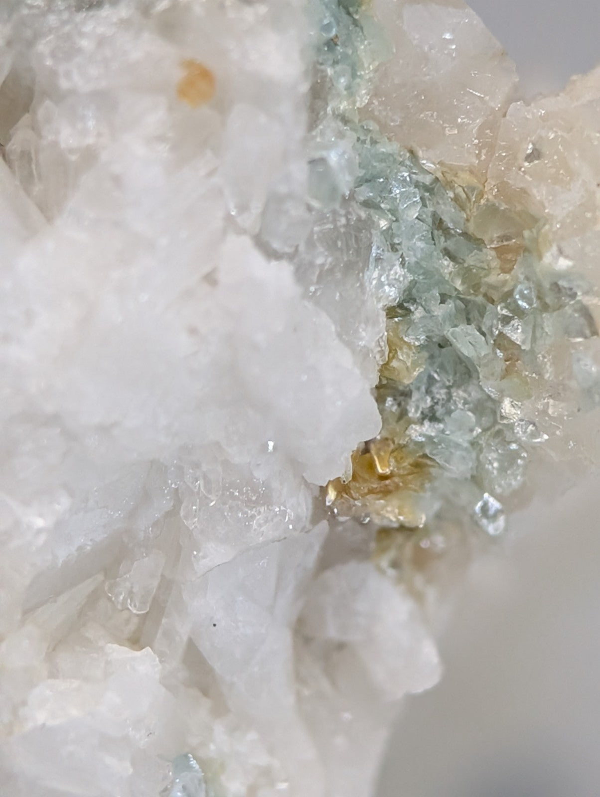A cluster of translucent white and pale green blue green cookeite crystals on quartz with golden inclusions from arkansas