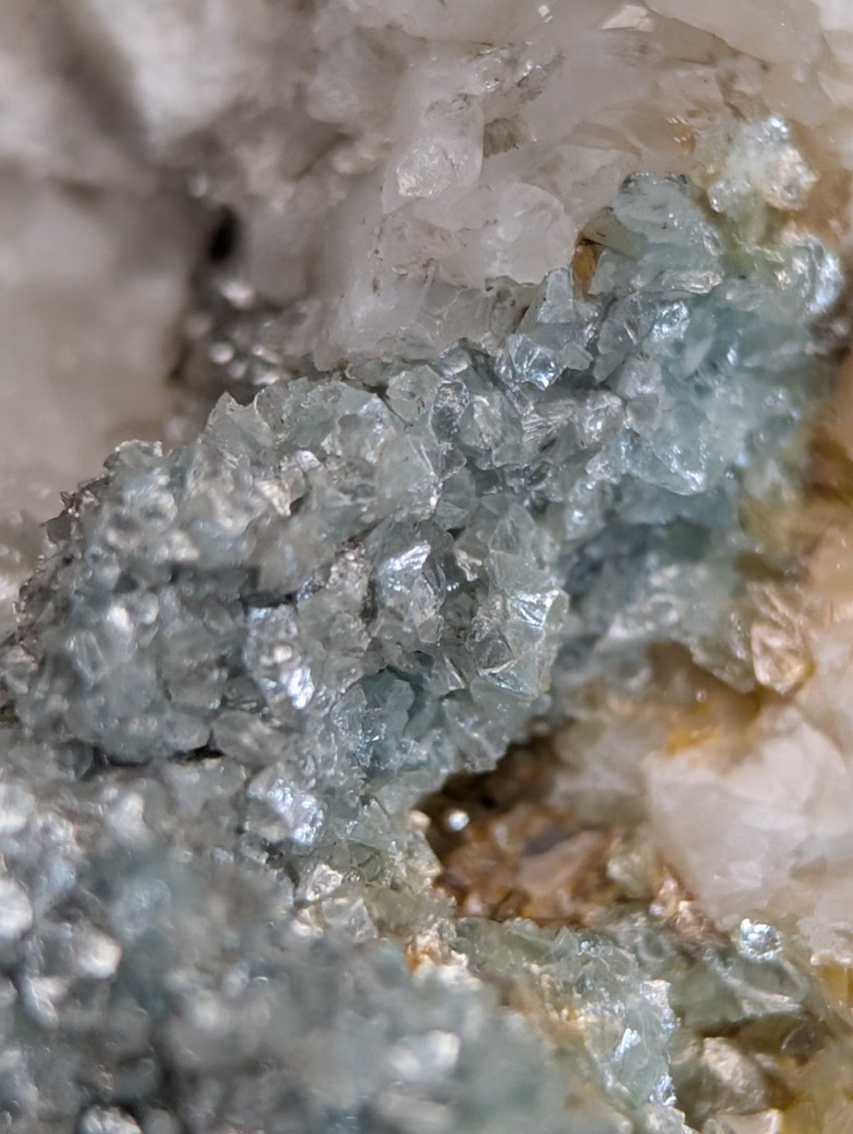 A cluster of translucent light blue blue green cookeite crystals on quartz with sharp edges and metallic sheen from arkansas