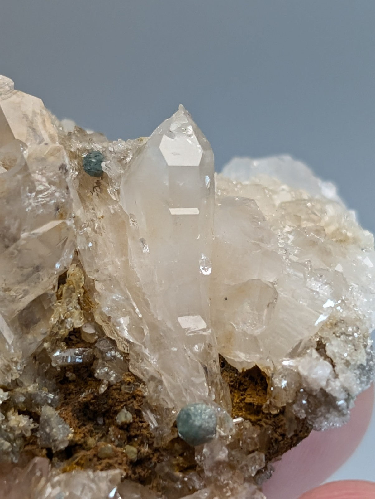 A translucent clear quartz crystal with pointed tip and internal striations showcasing blue green cookeite from Arkansas