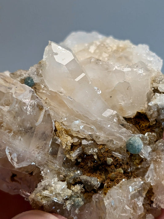 A translucent quartz crystal cluster with teal cookeite and golden mineral inclusions from saline county arkansas