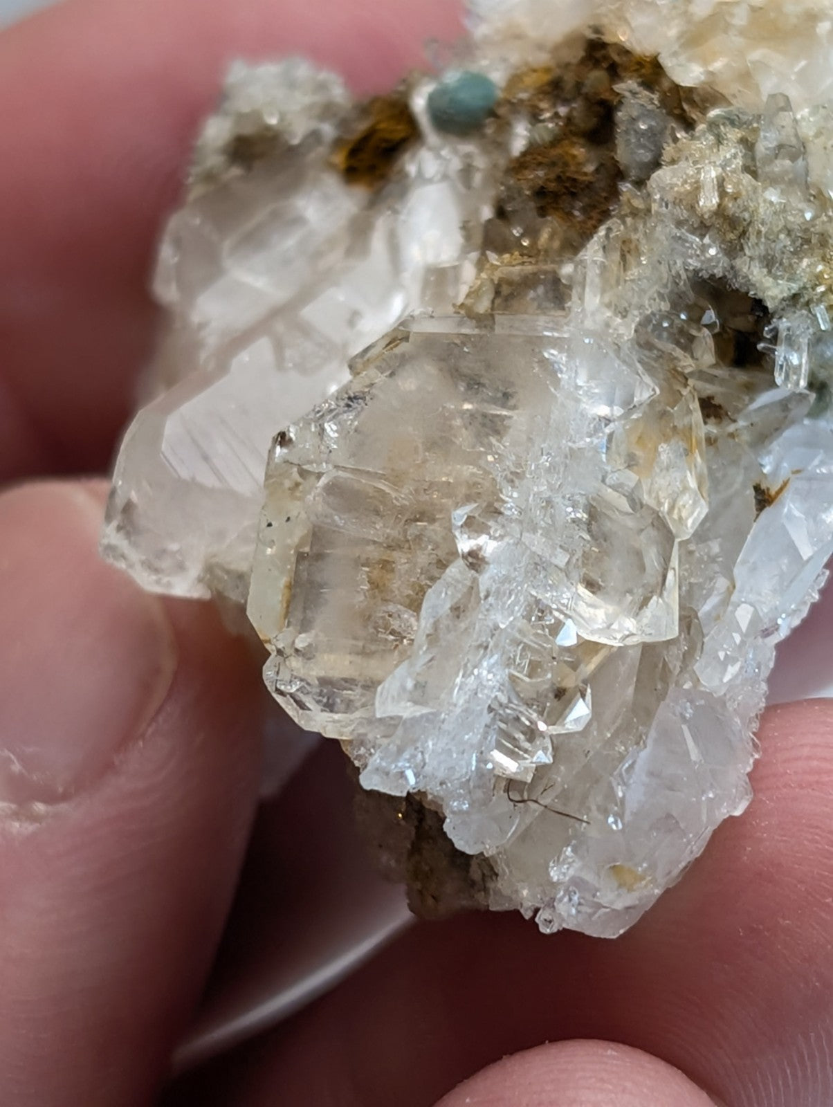 A cluster of translucent quartz crystals with golden and brown inclusions blue green cookeite on quartz saline arkansas