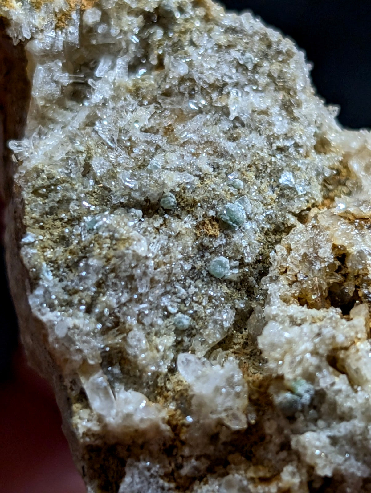 A rugged mineral specimen featuring translucent, crystalline formations in shades of white and pale green, embedded within a textured matrix of earthy brown and gray tones.