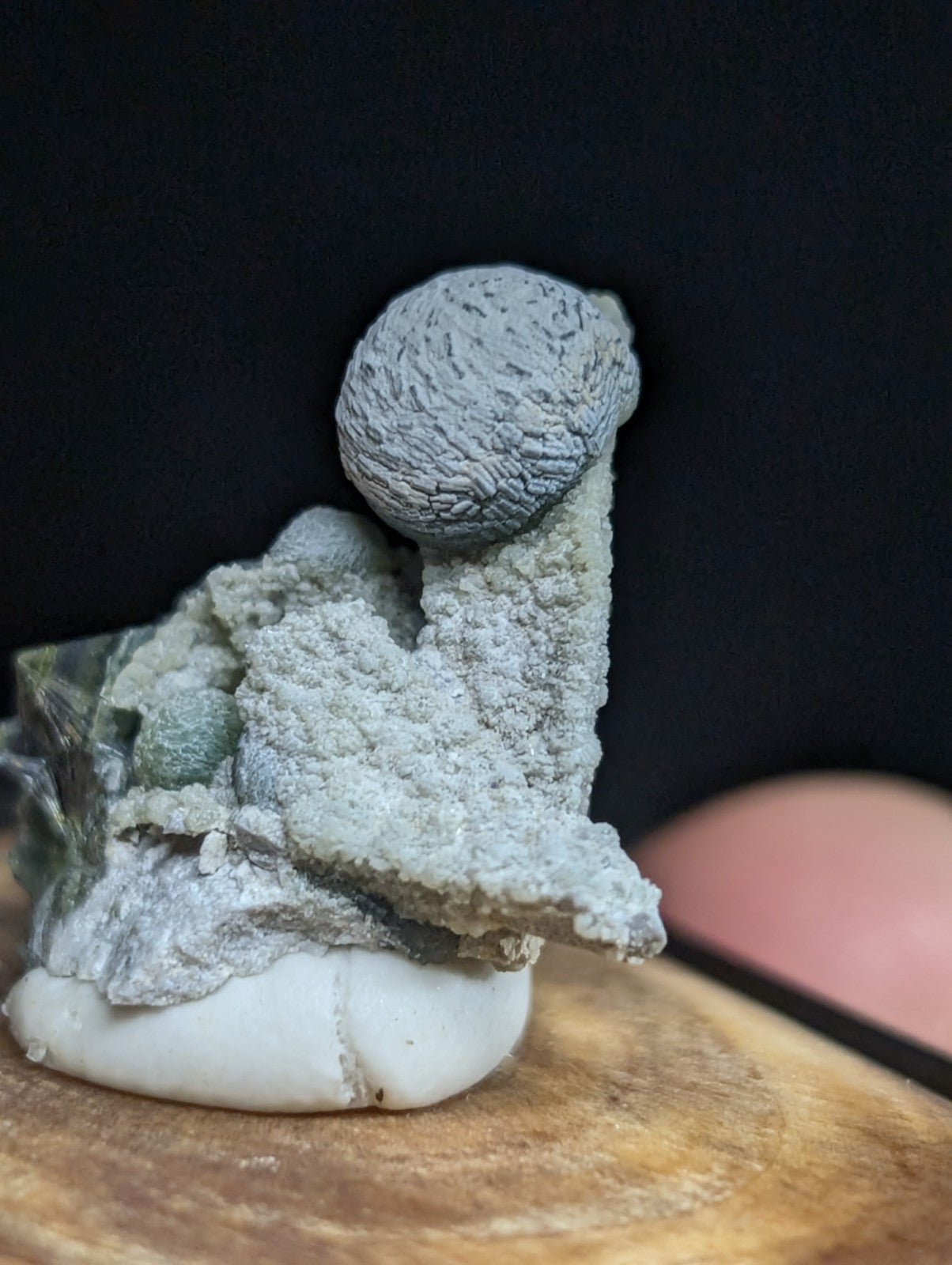 Gray, textured mineral specimen with a rounded top and crystalline base.