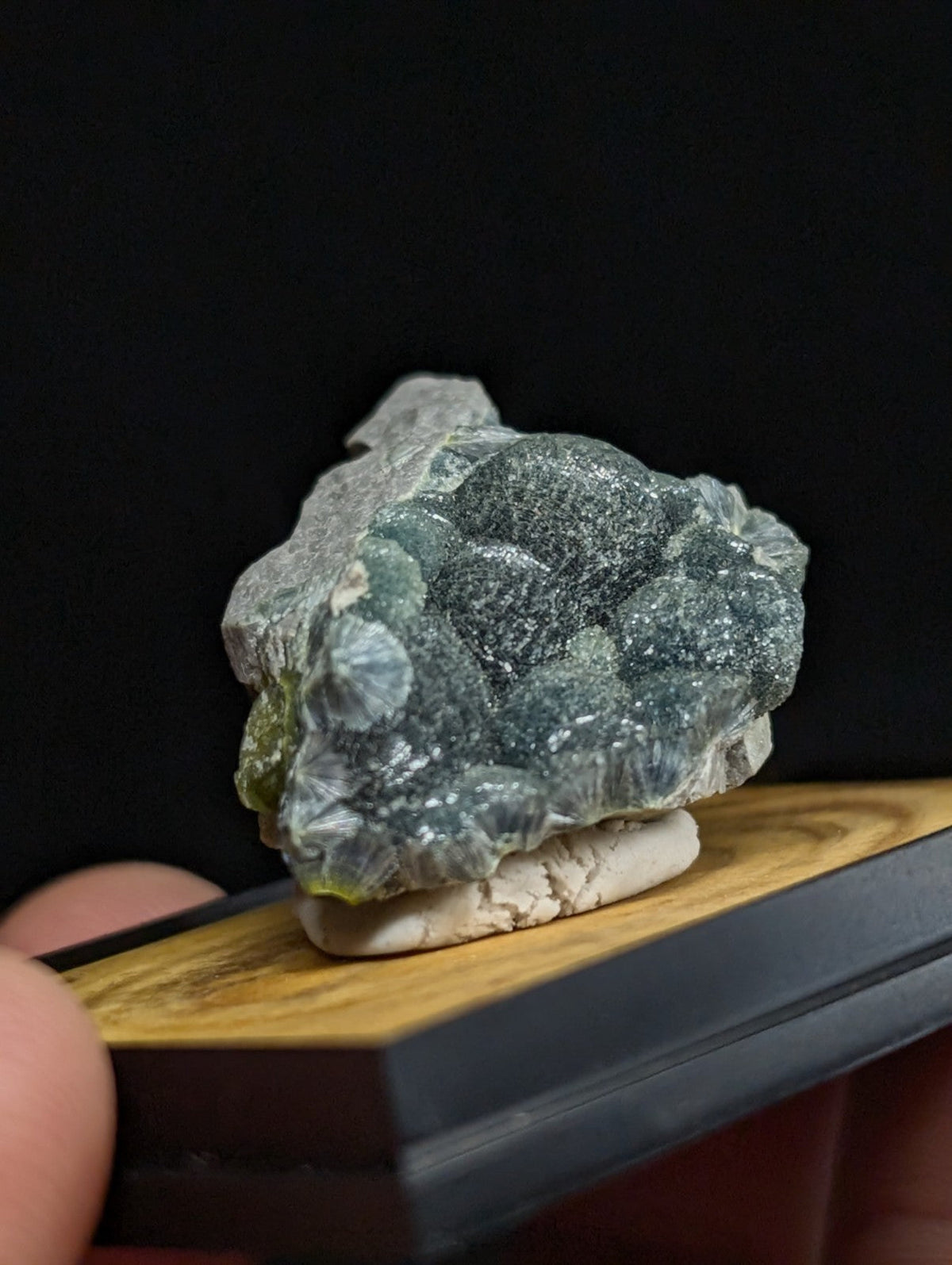 A textured, greenish-blue mineral specimen with a crystalline surface and speckled gray matrix.