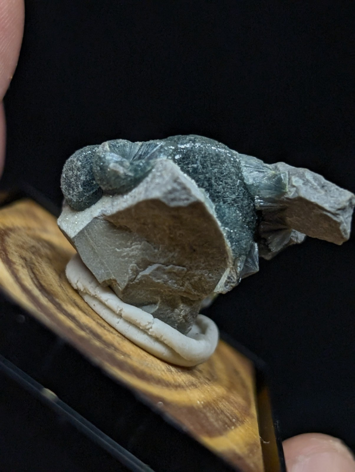 A translucent greenish-blue mineral specimen with a rough, jagged surface and embedded white crystalline formations.