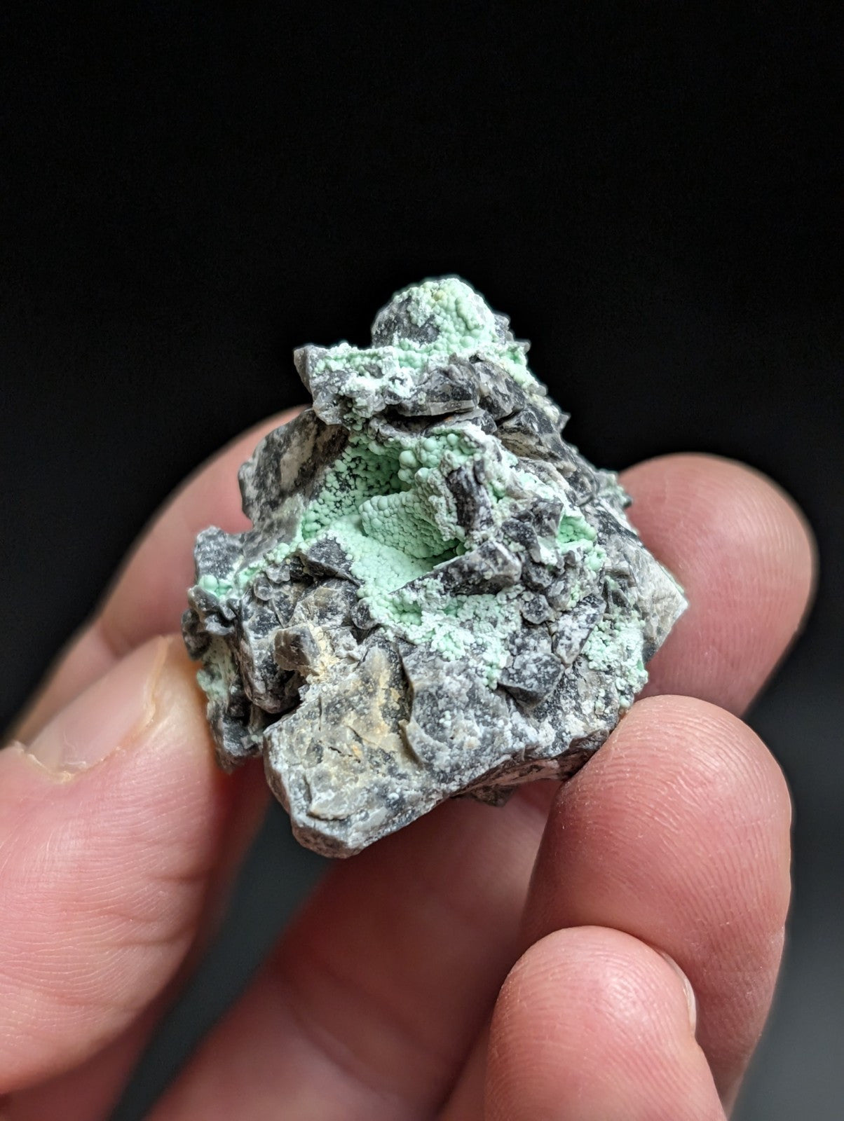 A rough, irregularly shaped mineral specimen with a mottled gray and vibrant green surface.