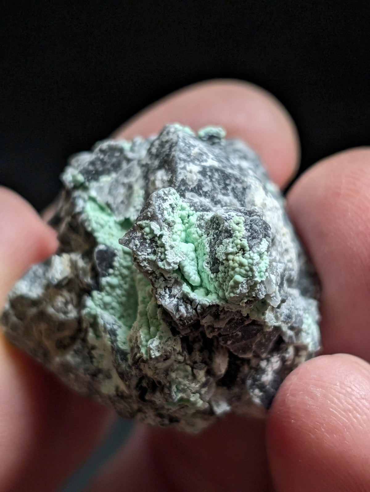 A rough, irregularly shaped mineral specimen with a mottled gray and vibrant green surface.
