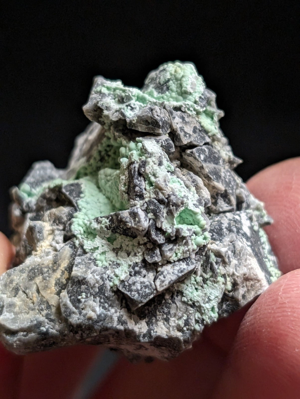 A rough, irregularly shaped mineral specimen with a mottled gray and vibrant green surface.