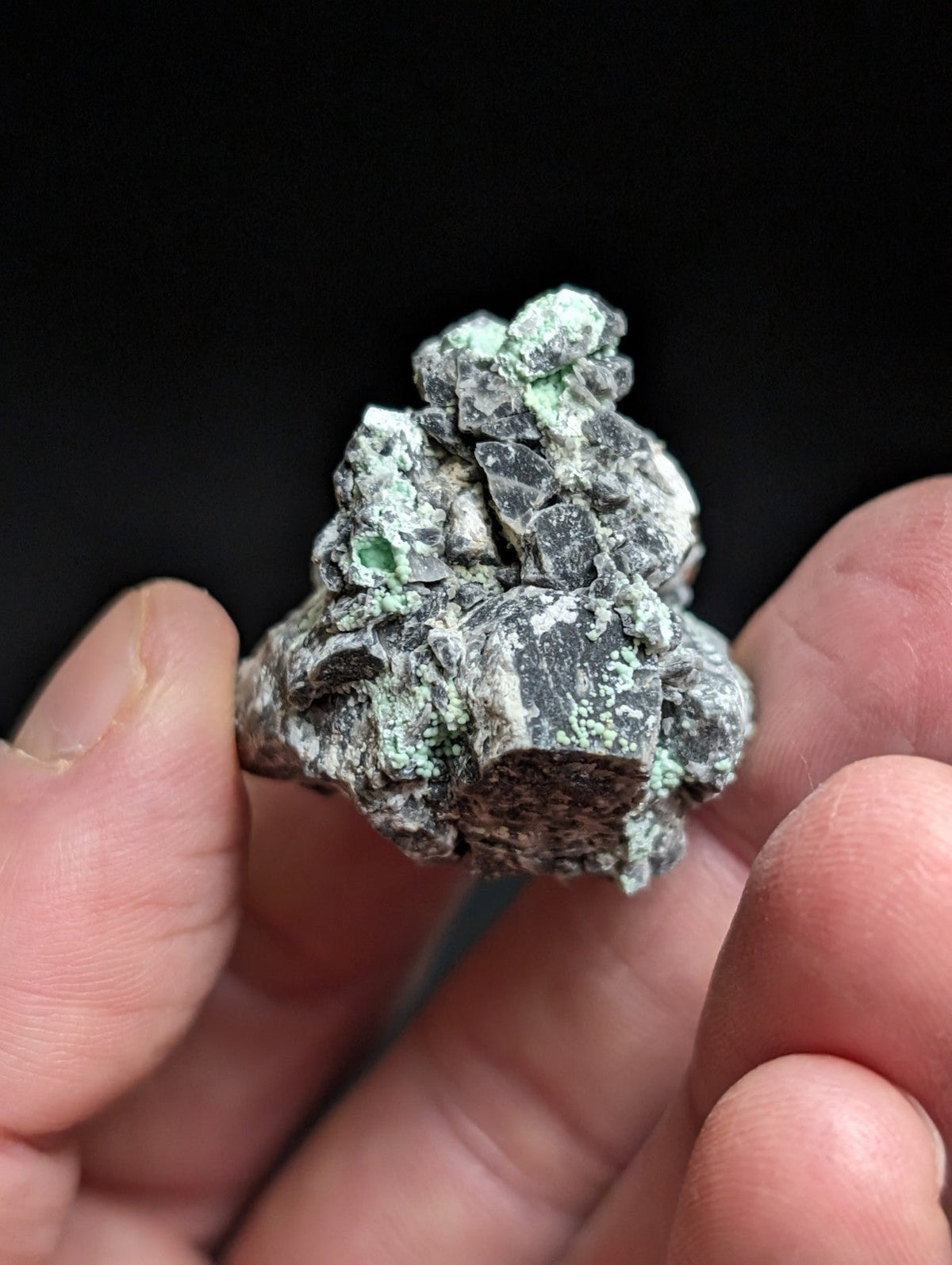 A rough, irregularly shaped mineral specimen with a mottled green and gray surface.