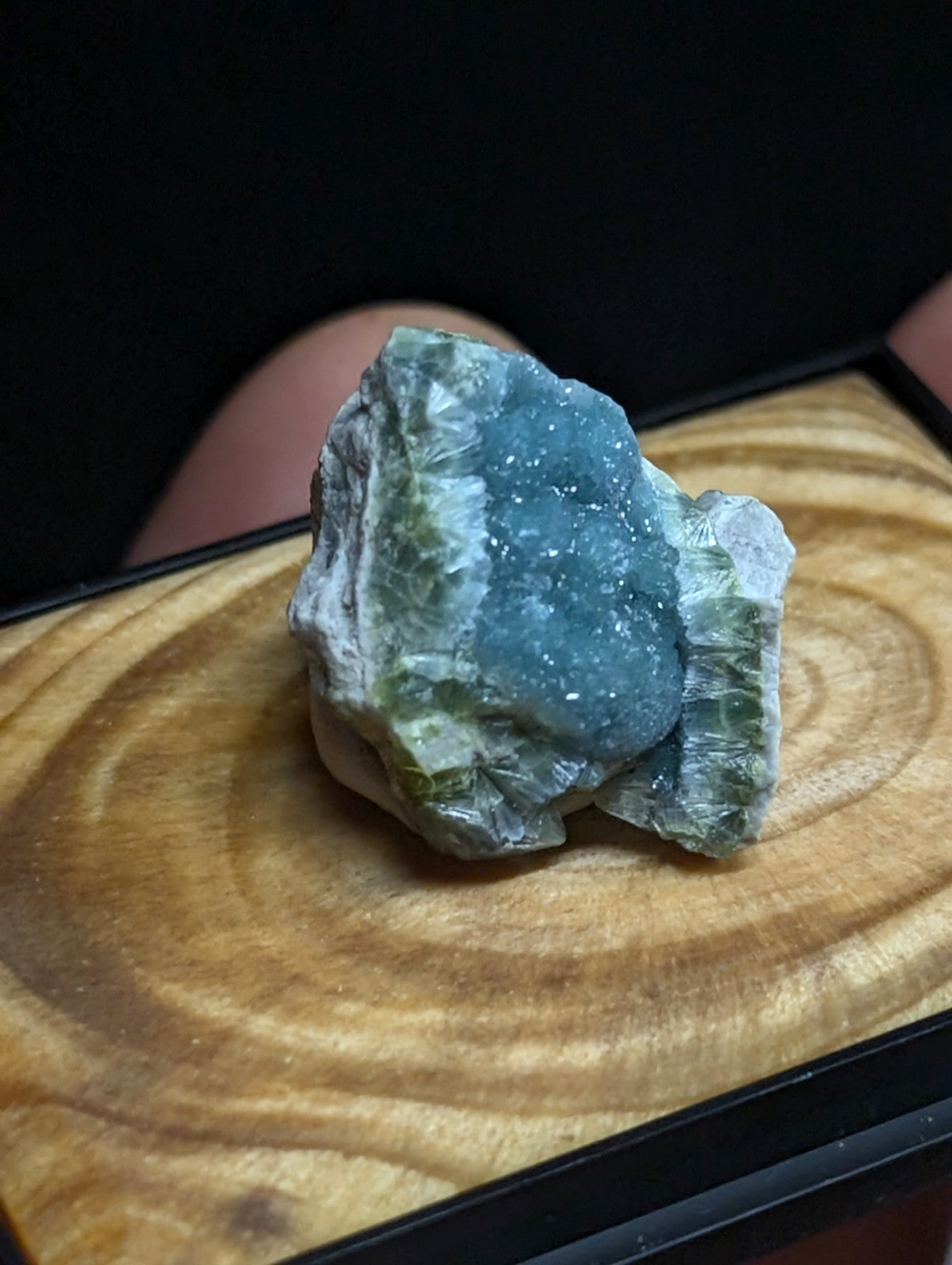 A striking blue-green mineral specimen with a crystalline, glittering surface and earthy green veining.