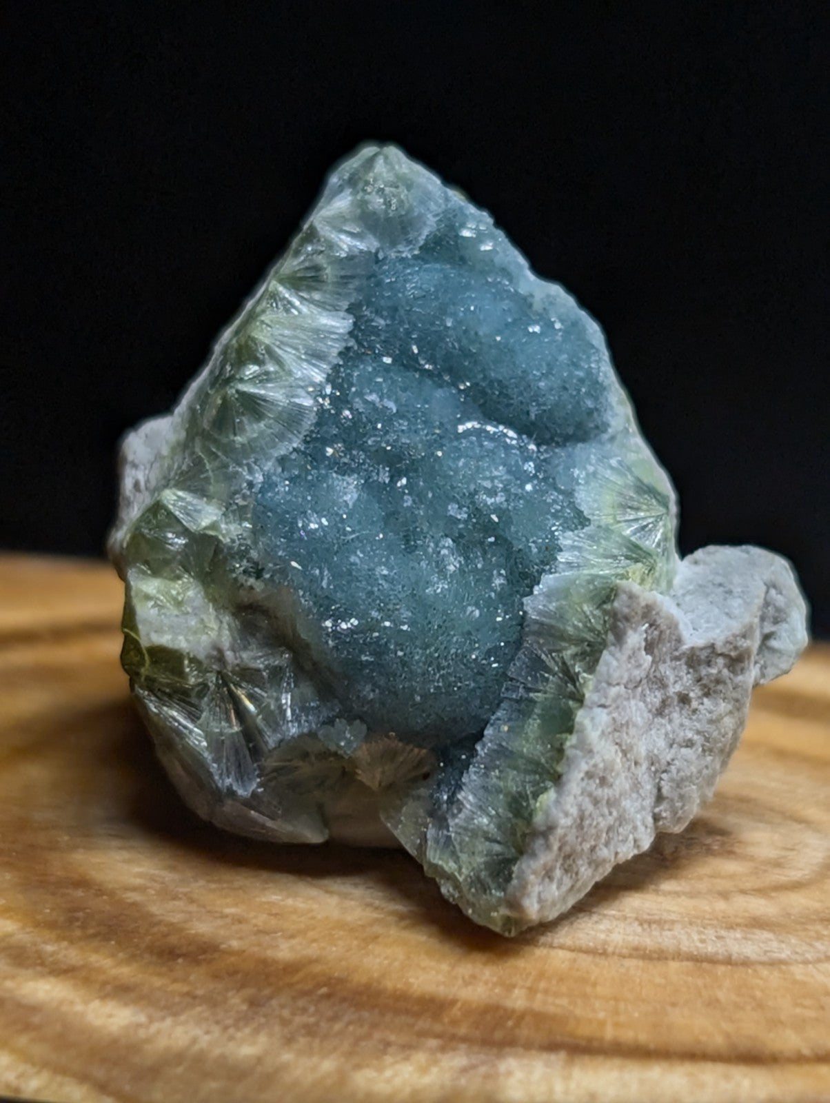 A striking blue-green druzy quartz geode with a crystalline, glittering surface and translucent greenish outer layers.