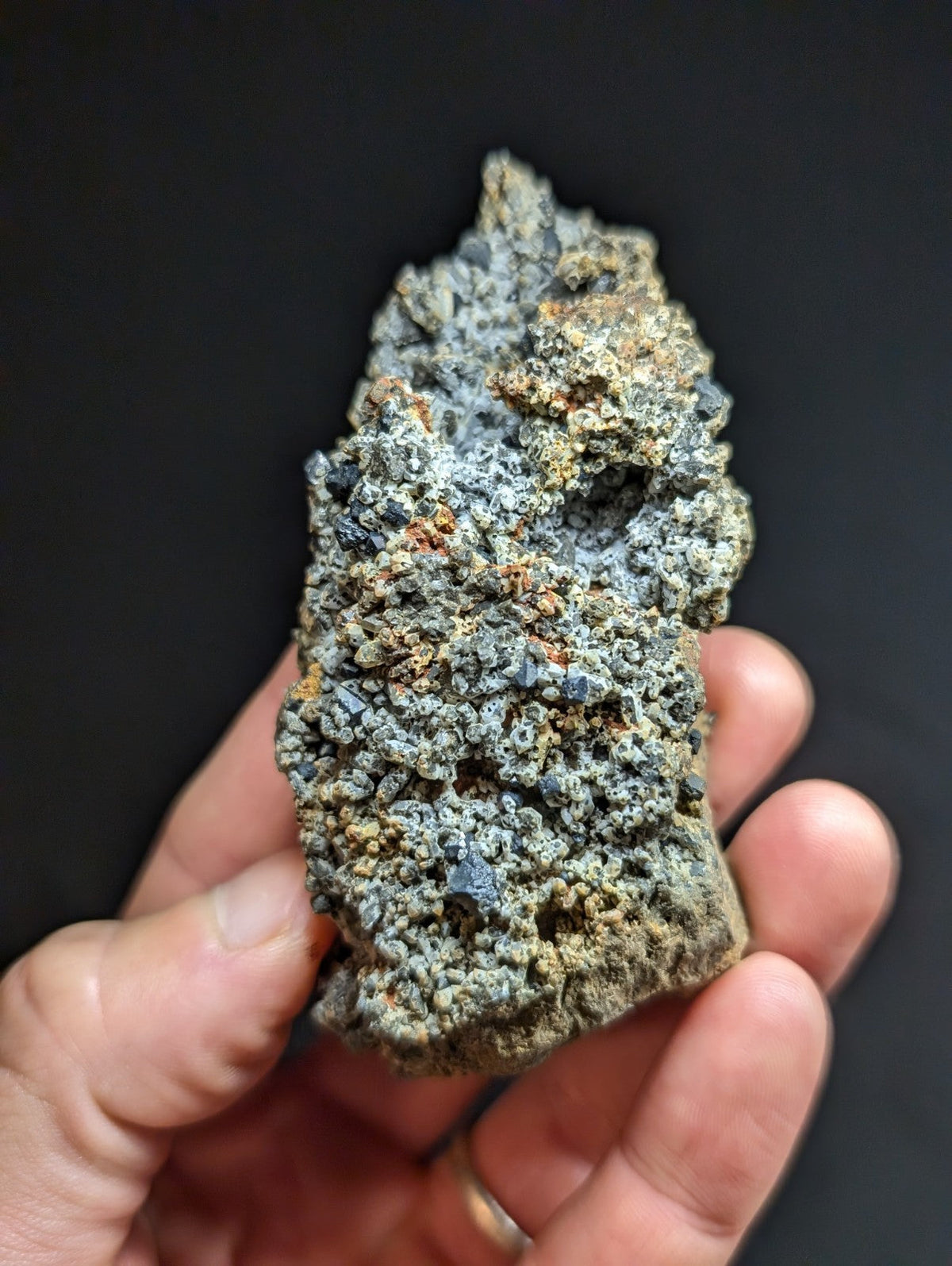 A rough, irregularly shaped mineral specimen with a textured surface displaying patches of grayish-blue and earthy brown tones.