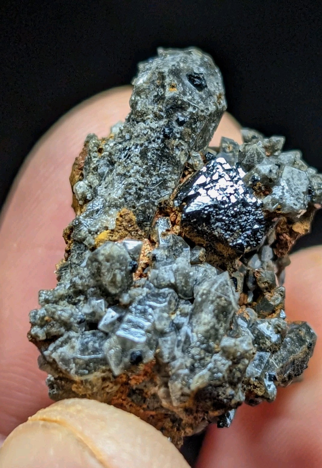 A cluster of gray, crystalline minerals with a metallic sheen and some black inclusions.