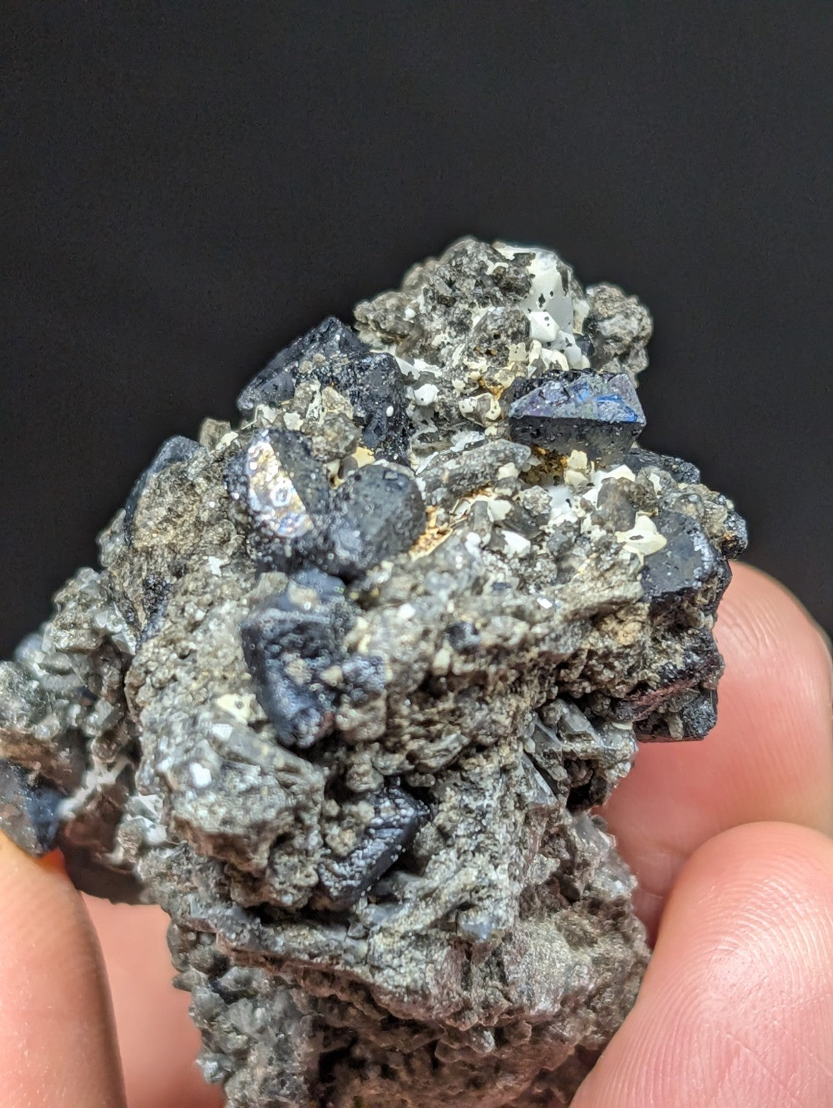 A rugged, dark gray mineral specimen with prominent deep blue crystalline formations embedded in a rough-textured matrix.
