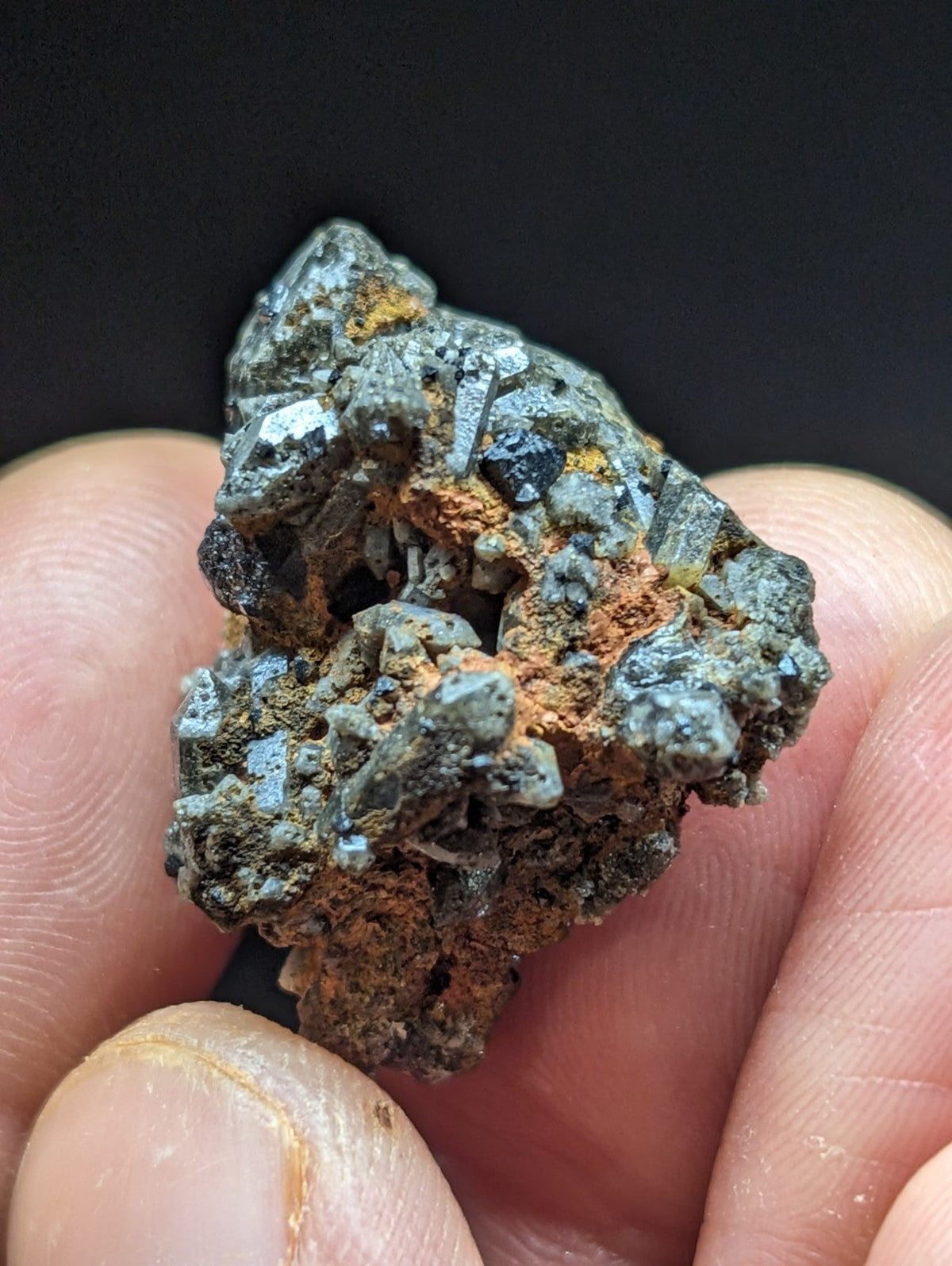 A rugged, irregularly shaped mineral specimen with a mix of dark gray and orange-brown hues, featuring crystalline textures.