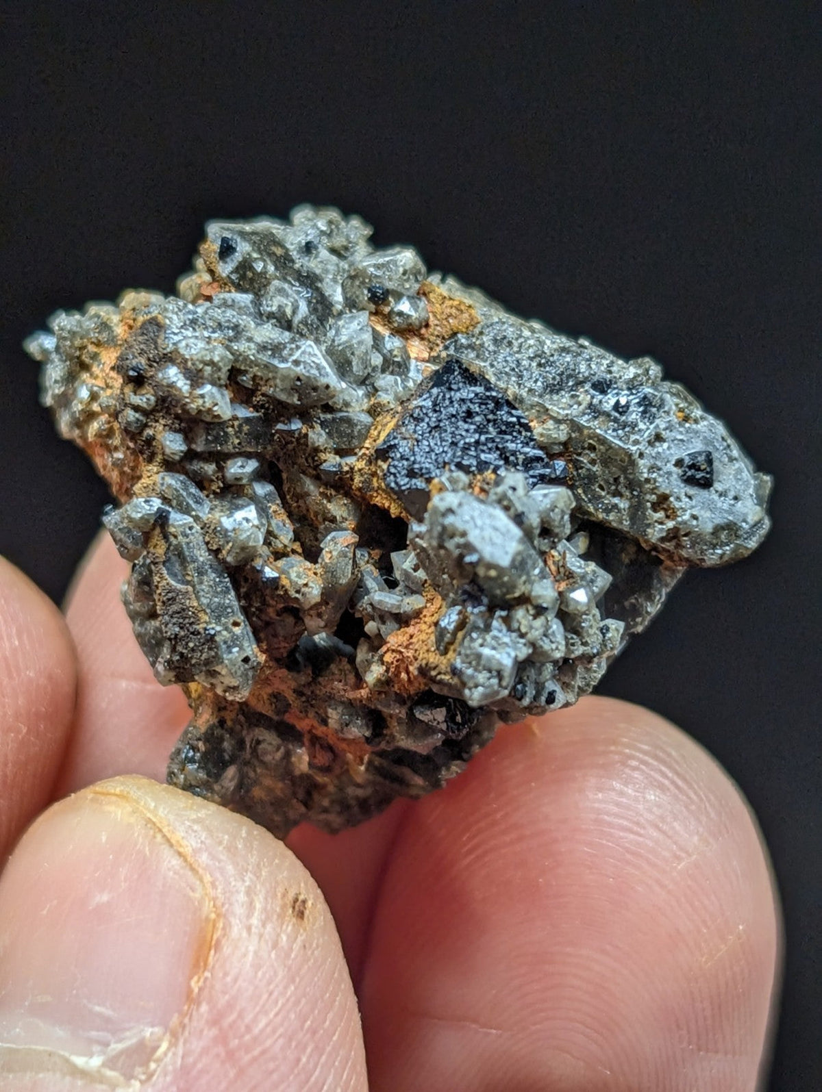 A rugged, grayish mineral specimen with crystalline formations and patches of orange rust.