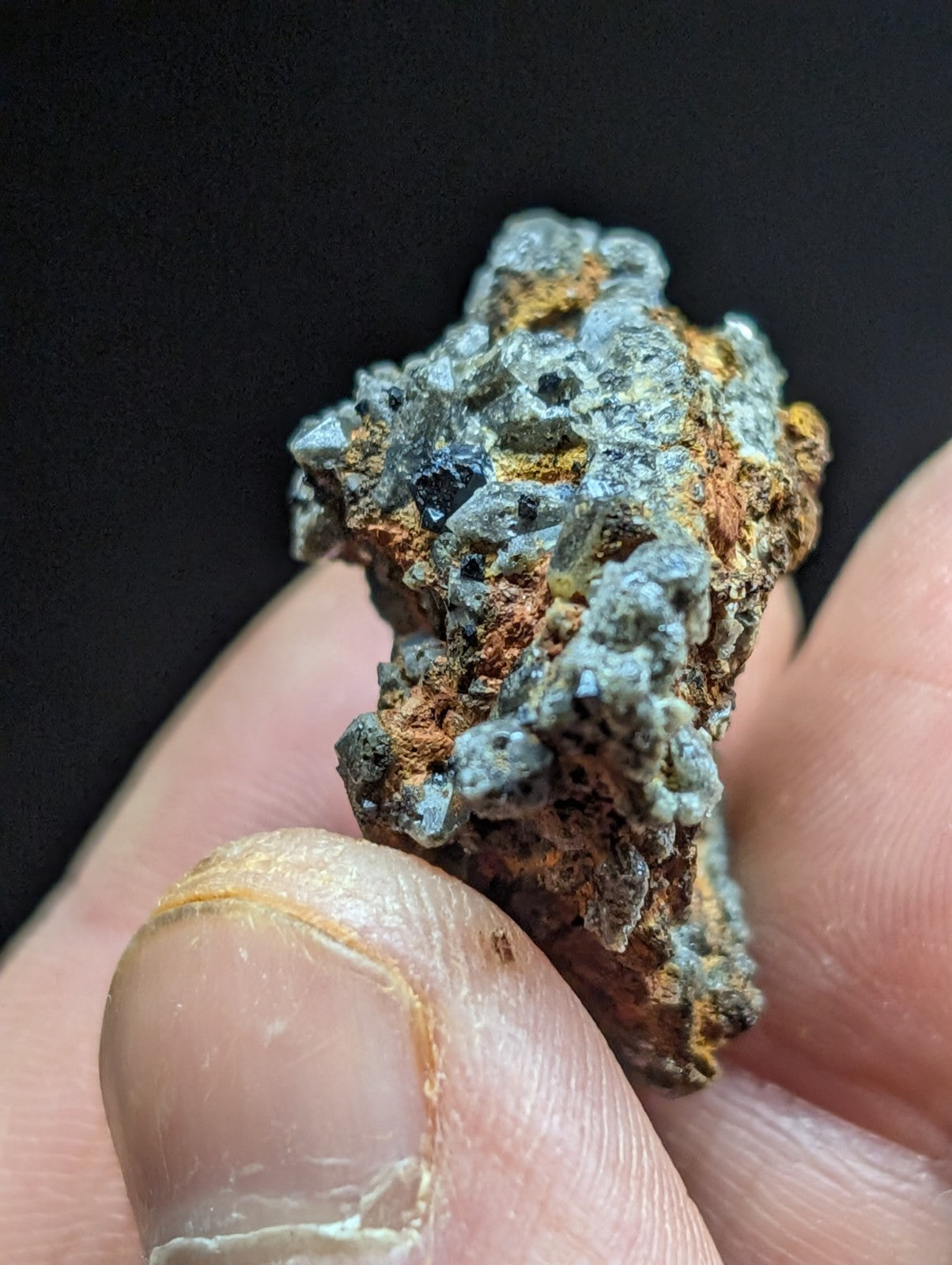 A rugged, irregularly shaped mineral specimen with a mix of grayish-blue crystalline formations and patches of orange-brown oxidation.