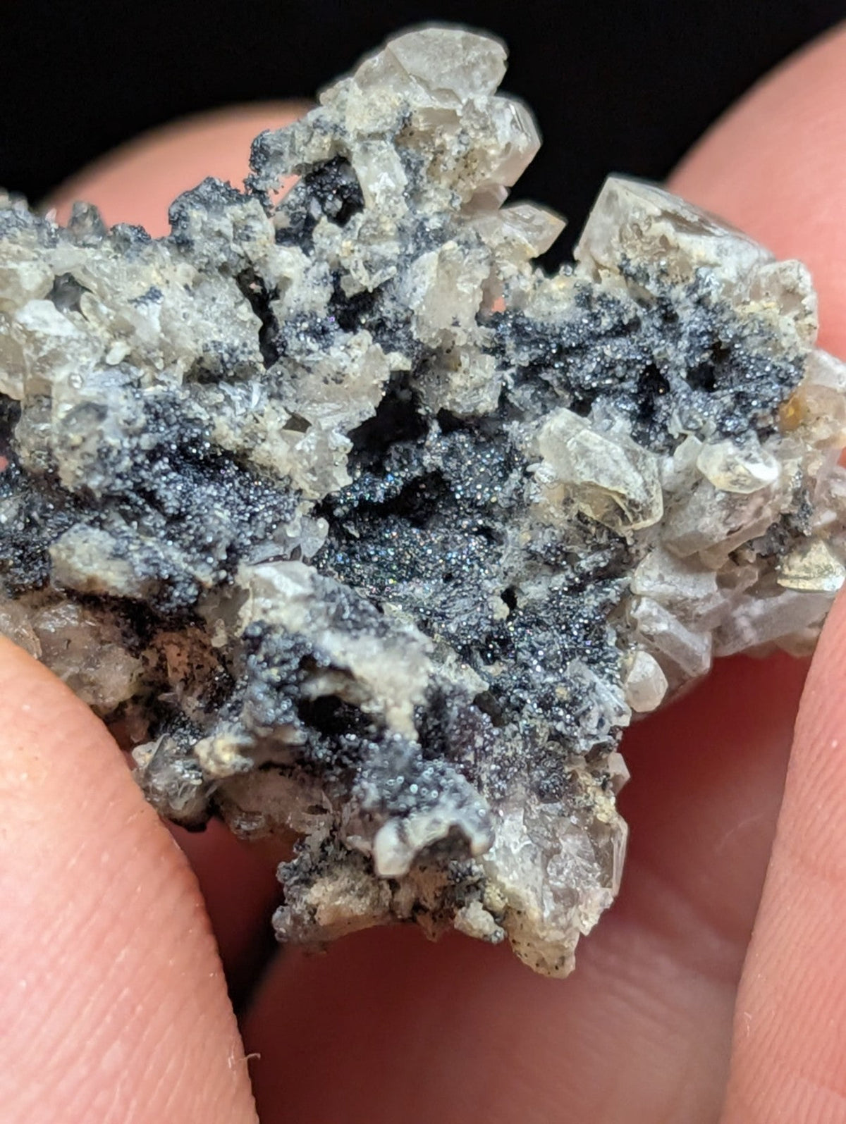 A textured mineral specimen featuring translucent, crystalline formations intermingled with dark gray to black metallic-looking patches.