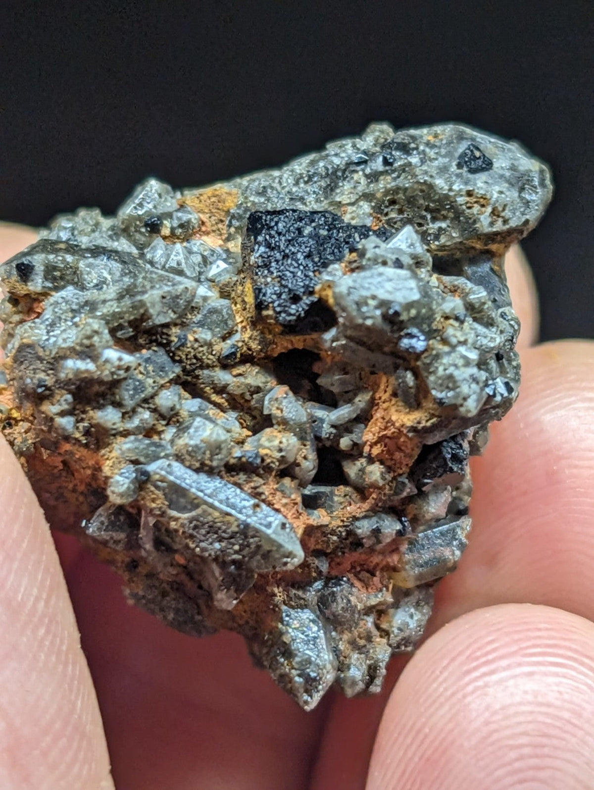 A rugged, irregularly shaped mineral specimen featuring a mix of gray crystalline formations and dark black patches with hints of orange rust.