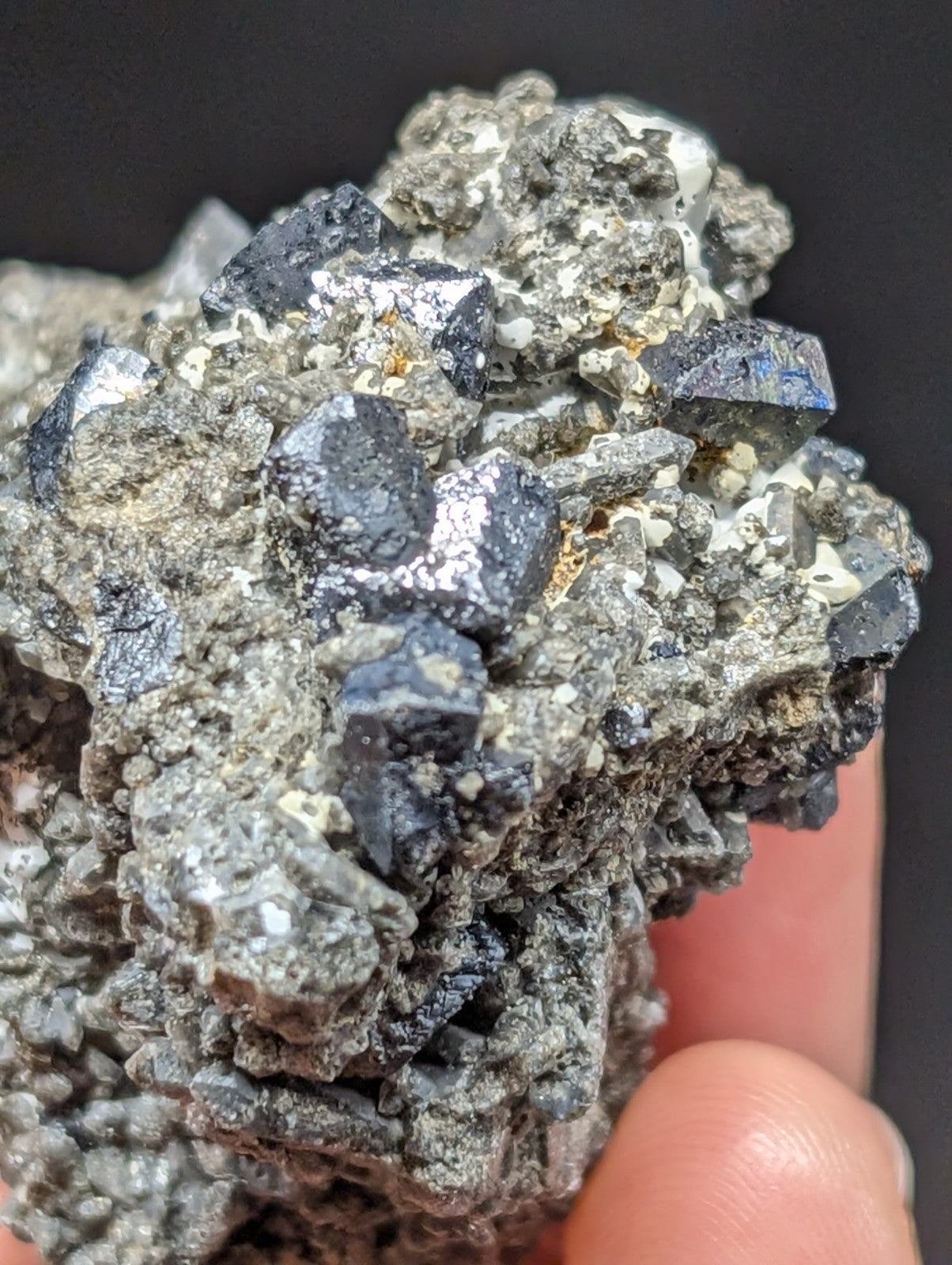 A cluster of dark, metallic-looking mineral crystals with a rough, jagged surface and some exhibiting subtle blueish reflections.