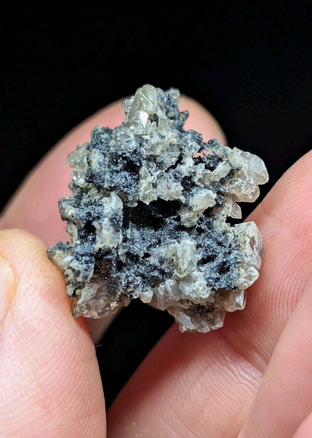 A textured mineral specimen with translucent gray crystals intermingled with dark, almost black matrix material.