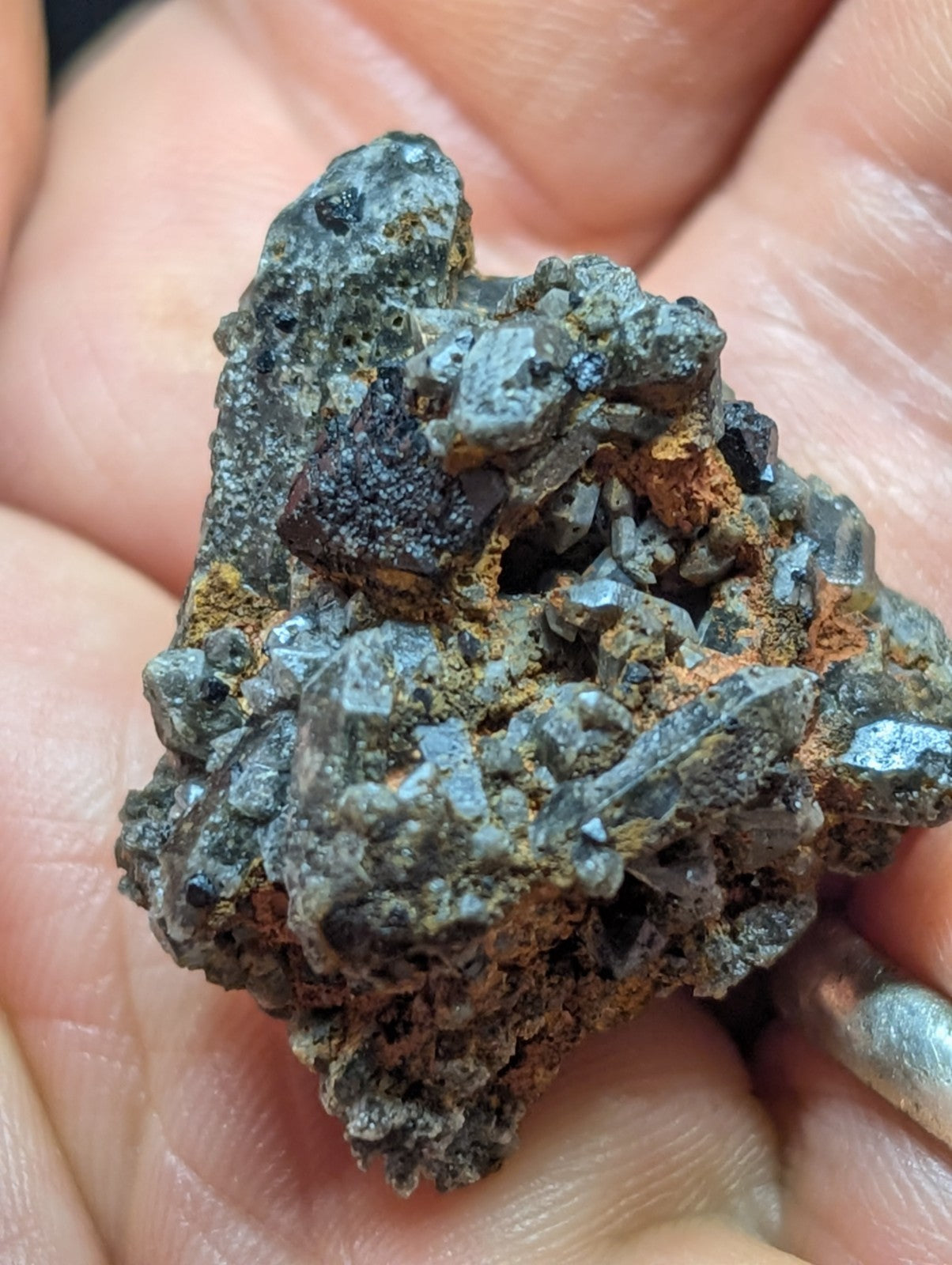 A rugged, dark gray mineral specimen with metallic sheen and patches of orange rust.