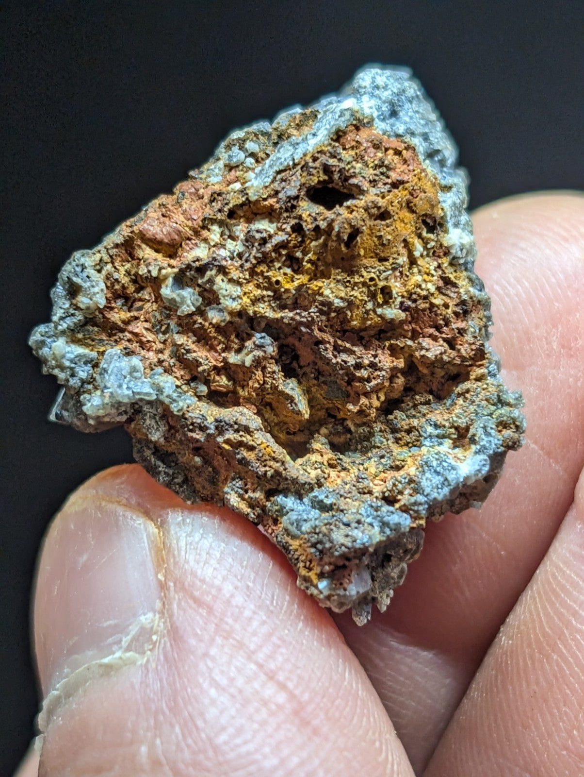 A rugged, irregularly shaped mineral specimen with a textured surface displaying patches of orange-brown and grayish-blue patina.