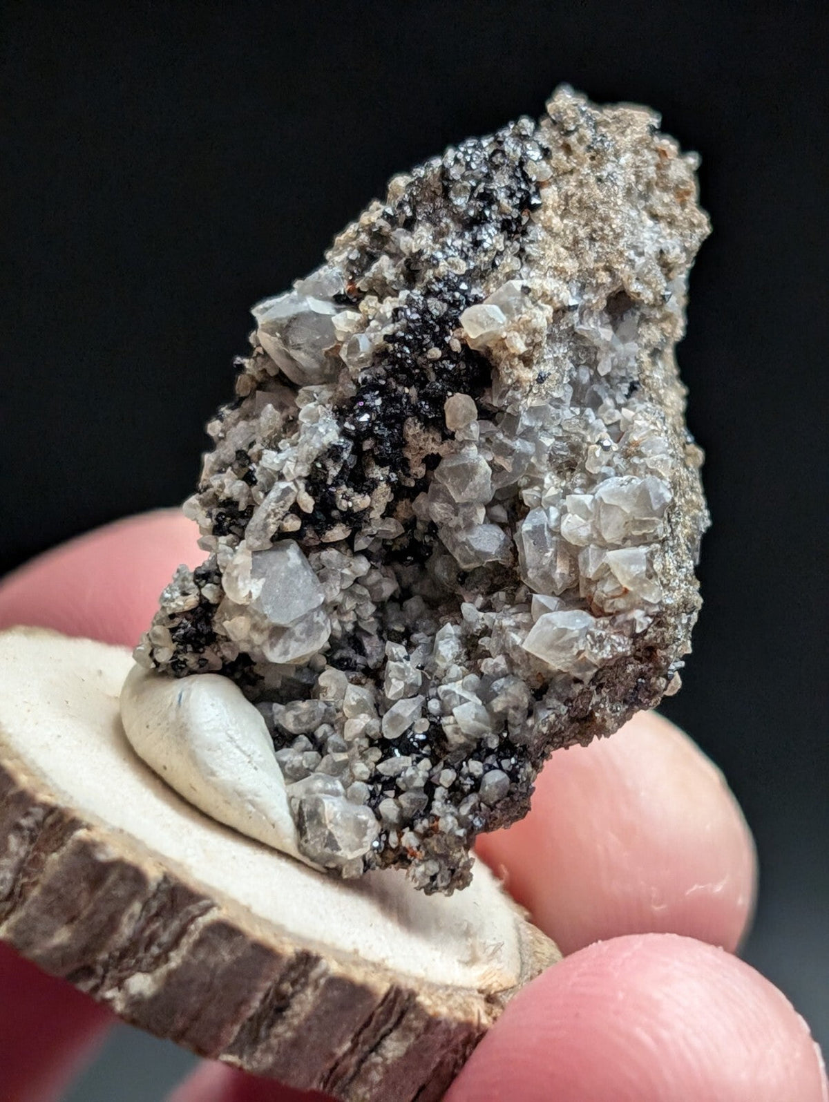A rugged, naturally formed mineral specimen featuring translucent gray crystals embedded in a dark matrix.