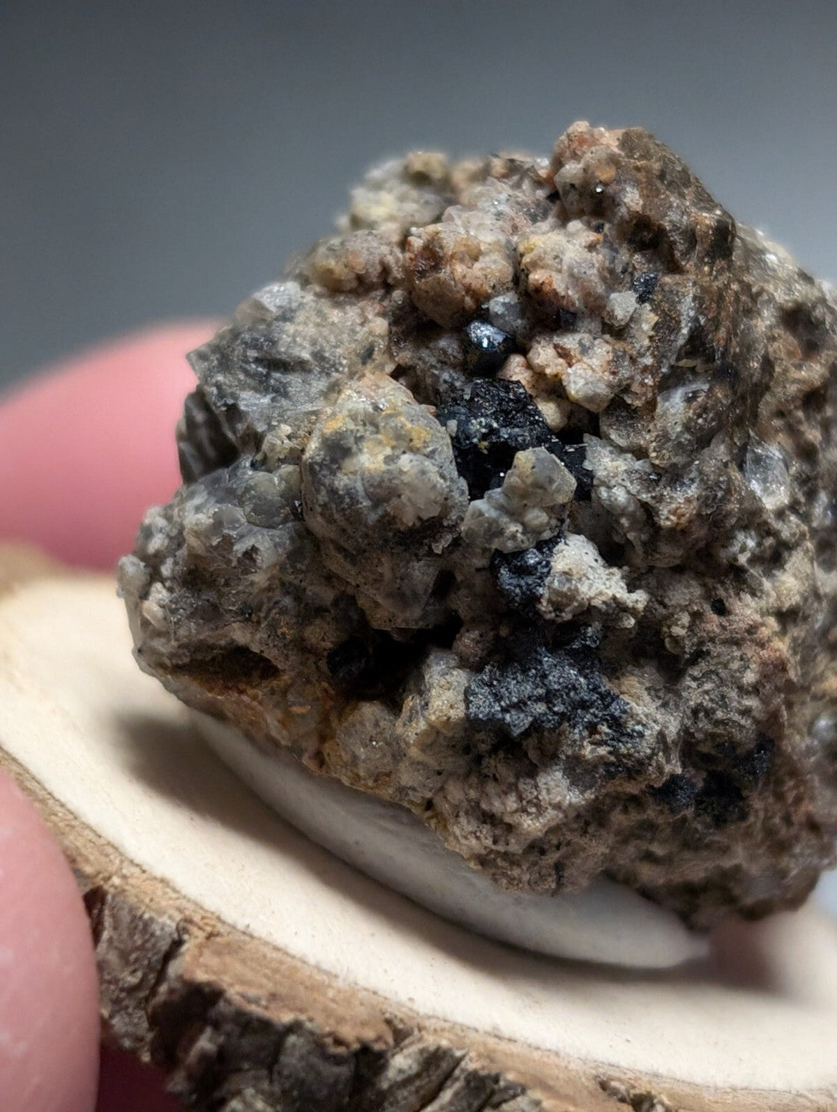 A rugged, textured mineral specimen with a mix of gray, brown, and dark black crystalline formations.