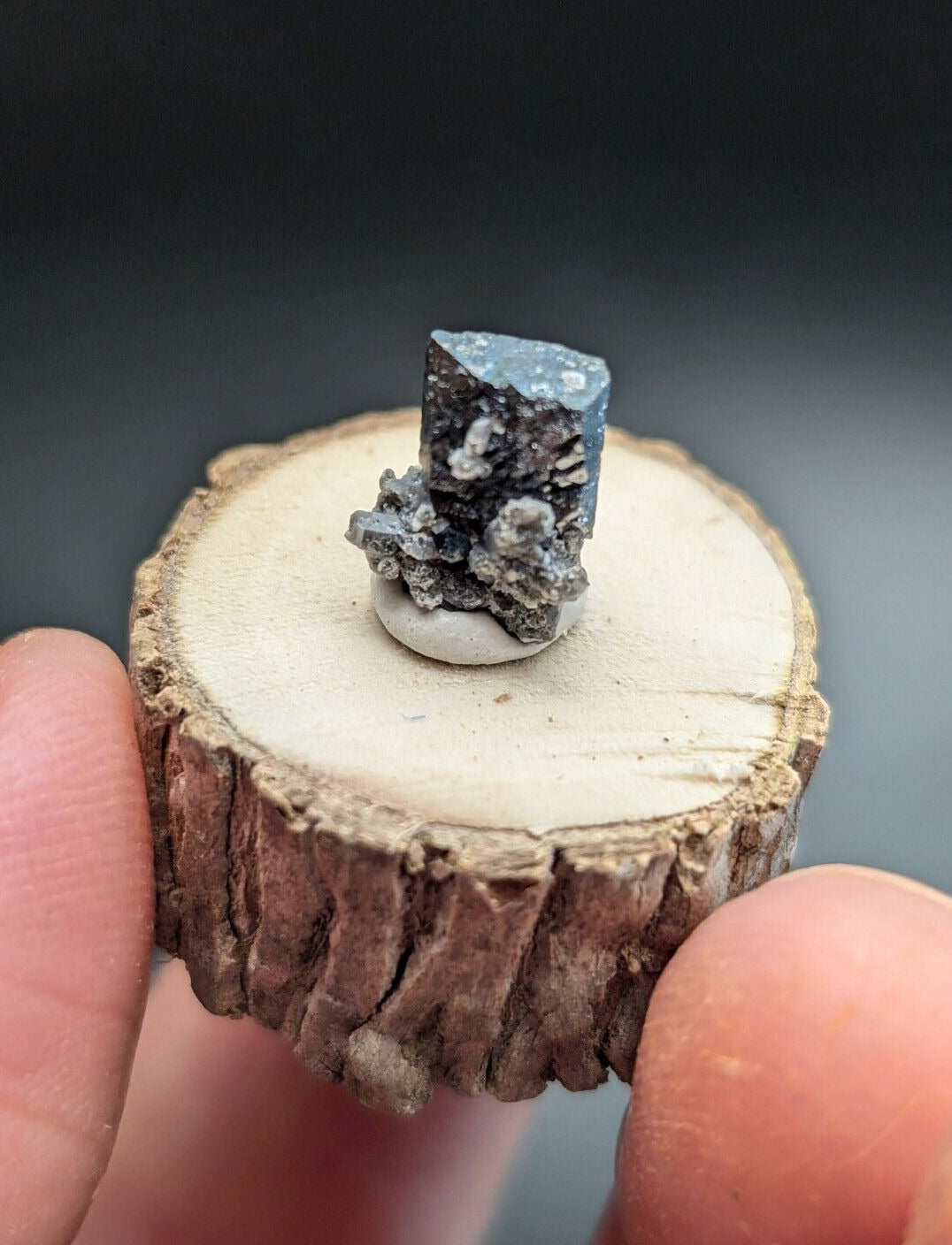 Bluish-gray crystal specimen on a wooden base.