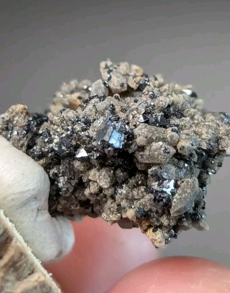 A cluster of dark gray and black mineral crystals with reflective, metallic facets.