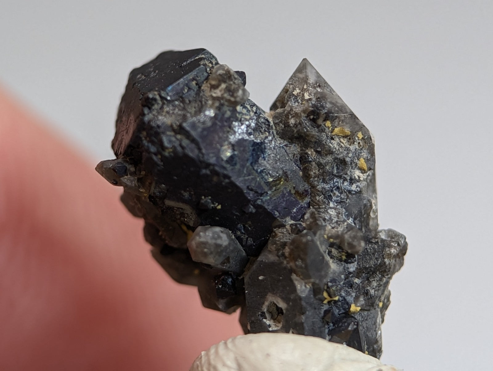 A dark brookite mineral on smoky quartz with yellow specks from magnet cove arkansas displayed on wood