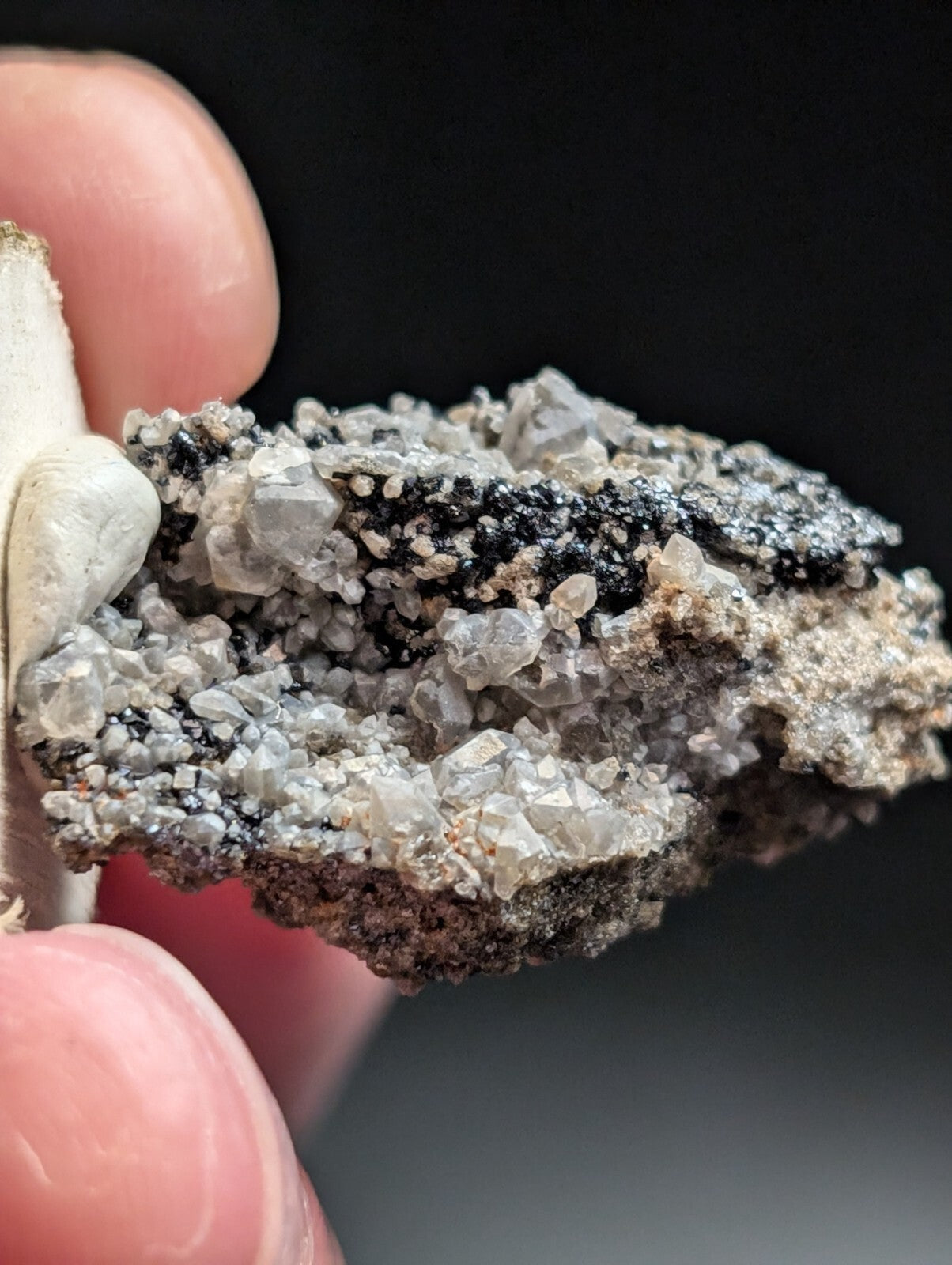 A rugged, naturally occurring mineral specimen featuring a striking contrast of translucent gray crystals and dark black matrix material.