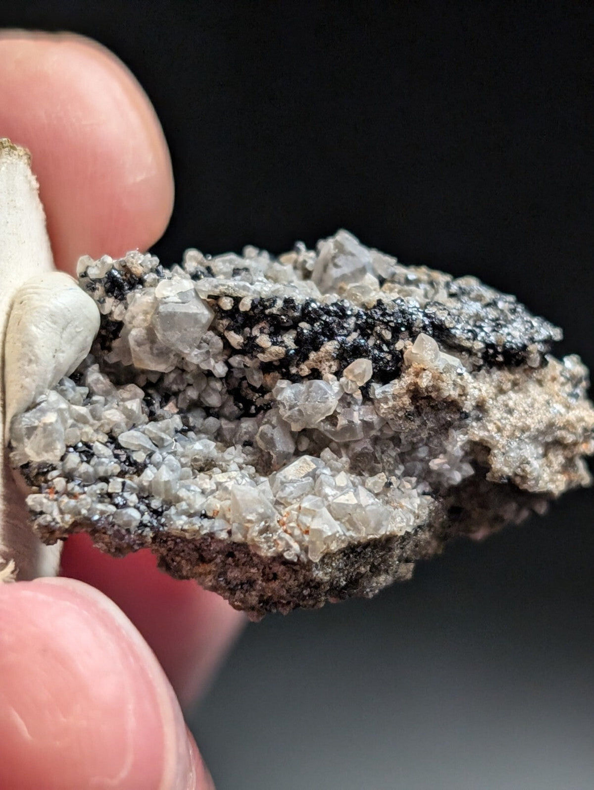 A rugged, naturally occurring mineral specimen featuring a striking contrast of translucent gray crystals and dark black matrix material.