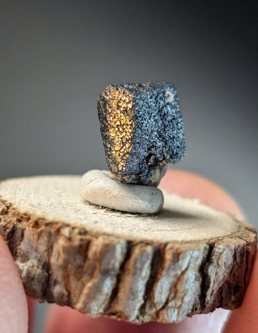 Metallic cube with gold and dark gray facets.
