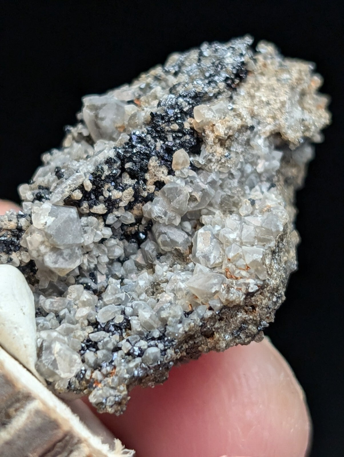 A rugged, naturally occurring mineral specimen featuring translucent gray crystals embedded in a dark matrix with patches of black and earthy tones.