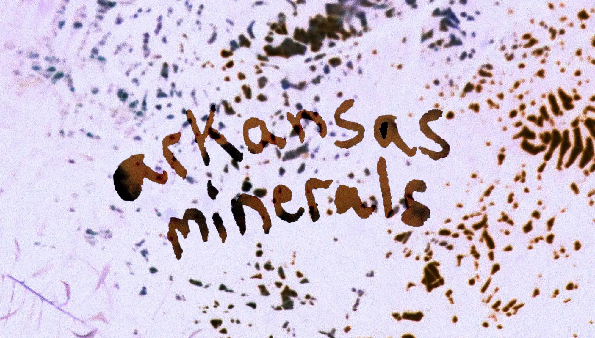 Brown cursive text reading ’arkansas minerals’ on a speckled, light-colored background.
