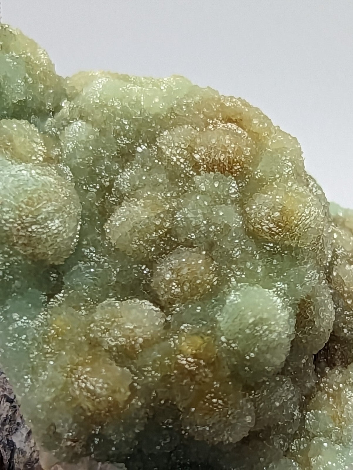 A cluster of translucent, bubble-like green and yellowish mineral formations with a crystalline texture.