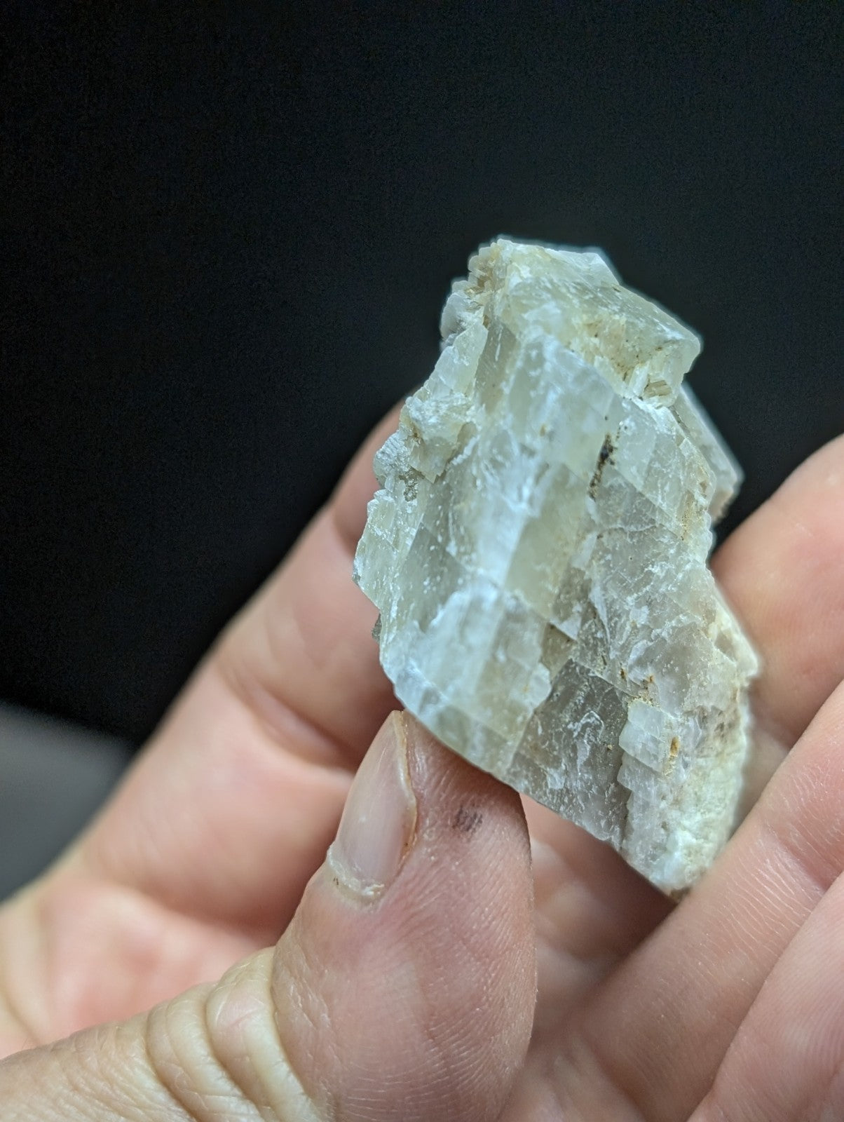 A translucent, pale green mineral specimen with crystalline facets and a rough, jagged surface.