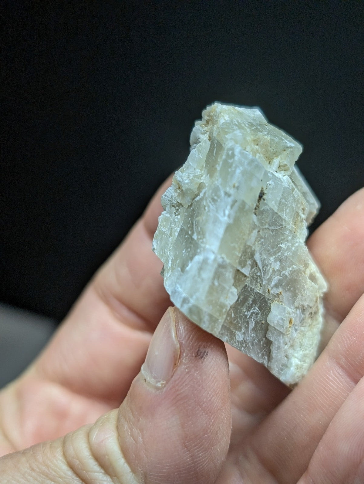 A translucent, pale green mineral specimen with crystalline facets and a rough, jagged surface.